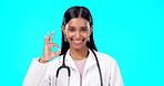 OK hand and woman doctor isolated on blue background for healthcare success and service support. Like, yes and agreement sign or emoji of Indian person or medical worker face or portrait in studio
