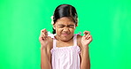 Child, wish and fingers crossed on green screen for luck or faith. Girl kid or eyes closed emoji for hope, praying and miracle or help on studio background space with mockup space while hopeful