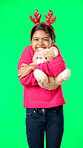 Christmas, teddy bear and happy with girl in green screen studio for hugging, celebration and festive. Present, cheerful and vacation with child on background for season, holiday and happiness