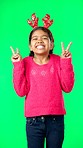 Girl child, peace sign and face by green screen studio in christmas mockup, reindeer costume or happiness. Emoji hands, kid and vertical portrait for holiday, festive cheer or happy childhood memory