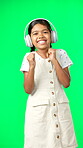 Children, music and dance with a girl on a green screen background in studio streaming audio. Portrait, smile and fun with an adorable little girl dancing while listening to the radio on headphones
