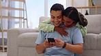 Love, hugging and couple on a phone in living room browsing on social media or the internet. Happy, smile and young woman embracing her husband while networking on mobile app with cellphone at home.