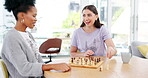 Friends, chess and board game and checkmate with the winner laughing and thinking about plan. Diversity women together at table in room happy about competition move and strategy to win on chessboard