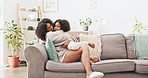 Love, happy and mother hugging her child while relaxing on a sofa in the living room of their home. Happiness, bonding and young mom embracing and kissing her girl kid with care in their family house