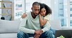 Sad, laptop and couple with paperwork for finance debt, taxes or expenses on sofa in home. Interracial, documents and woman comfort and hug depressed black man for problem, bills or financial crisis.