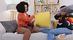 Love, pillow fight and couple on couch, bonding or quality time in living room, happiness or relax together. Romance, black man or woman on sofa, playful or relationship with joy or friends in lounge