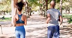 Fitness, running and couple in park from back for exercise and bonding in nature together. Marathon training, black man and woman run on garden path for health, wellness and workout with green trees.