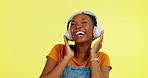 Music, studio dance and happy black woman dancing to song, wellness audio podcast or radio sound track. Headphones, dancer freedom energy and streaming African person listening on orange background