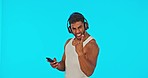 Rock, face and a man with a phone and music isolated on a blue background in a studio. Portrait, enjoying and a guy listening to the radio with headphones while gesturing a sign and on a mobile app