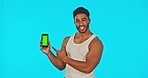 Face, green screen and man with phone pointing in studio isolated on a blue background. Cellphone, portrait and smile of happy Indian male with advertising, marketing or mockup for product placement.