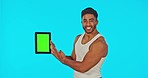Digital tablet, green screen and face of man pointing in studio for fitness, advertising and hand gesture on blue background. Portrait, mockup and man with app for health, exercise and gym progress