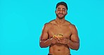 Man eating a sandwich in a studio for health, diet or wellness after an intense gym exercise. Happy, smile and portrait of a male model enjoying a meal for dinner after a workout by a blue background