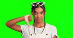 Woman, thumbs down and face by green screen for disagree, review and bad news by background. Girl, young Indian model and portrait with feedback, emoji and negative with hand sign for announcement