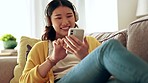 Woman, headphones and phone in a living room with happiness from music and texting. Home, lounge sofa and smile of a Asian female and gen z student feeling relax from audio and web podcast on couch