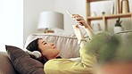 Woman, headphones and phone texting in a living room with happiness from music and mobile. Home, lounge sofa and smile of a Asian female and gen z student relax from audio and web podcast on couch