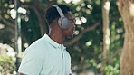 Happy, walking and a black man with music in nature for enjoyment, dancing and relaxation. Smile, dance and a young African guy with headphones for a podcast, audio and radio on a walk in a park