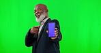 Phone, green screen and face of man isolated on studio background, tracking marker and mockup space for marketing. Senior african person pointing to cellphone, smartphone or mobile app design mock up