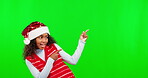 Christmas, happy and girl showing mockup on green screen isolated on a studio background. Festive, presentation and a young child gesturing to mock up chromakey space for an advertisement on backdrop