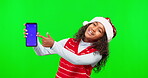 Pointing, Christmas and phone screen with child in green screen for news, message and social media. Digital, mockup and technology with young girl on studio background for holiday, festive and gift