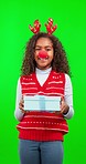 Christmas, gift and child in a studio with green screen with a festive reindeer costume. Happy, smile and portrait of girl kid model with present and xmas holiday accessories by chroma key background