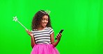 Phone, girl and princess on green screen with magic wand in studio isolated on a background mockup. Costume, crown or happiness of kid with cellphone for social media or online browsing on chroma key