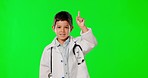 Doctor, green screen and a child pointing to space isolated on a studio background. Happy, healthcare and face portrait of a boy dressed as a medical professional gesturing to mockup or with an idea