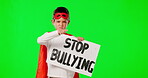 Face, stop bullying and boy with sign, green screen and costume against a studio background. Portrait, male child and young person with mask, superhero and protest for opinion for human rights 