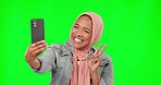 Happy muslim woman, selfie and green screen with peace, kiss and funny face for social media by background. Gen z girl, islamic influencer and photography with smile, fashion and mockup for web blog