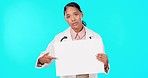 Doctor, woman and pointing at blank poster with mockup space for advice, healthcare and promotion by blue background. Young, female medic and paper board for logo, brand and portrait for wellness