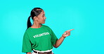 Volunteer woman pointing to empty space isolated on blue background text, product placement or advertising. Ngo, nonprofit and charity worker or biracial person face in studio, promo or presentation