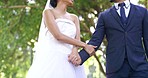 Wedding, park and couple walking and holding hands for marriage ceremony, commitment and celebration. Relationship, partnership and happy bride and groom walk in nature for romance, trust and love