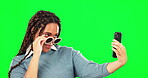 Selfie, sunglasses and attitude with a woman on a green screen background in studio for a profile picture. Photograph, fashion and style with a cool young female posing for social media status update