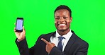 Phone, mockup and man in studio with green screen pointing at space for advertising or marketing. Happy, portrait and African male model showing mock up on cellphone isolated by chroma key background
