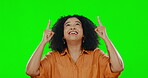 Hands, pointing and up with a woman on a green screen background in studio to promote product mockup. Hand gesture, happy and smile with a young female showing empty chromakey space above her head