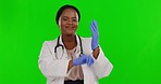 Face, green screen and black woman with doctor, putting gloves on hands and smile against studio background. Portrait, female employee and medical professional with safety regulations and protection