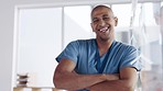 Happy, confidence and face of a doctor in his office after a consultation in the hospital. Happiness, smile and portrait of a male healthcare worker standing with crossed arms in a medical clinic.