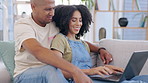 Laptop, couple and typing on sofa in home living room, social media or web browsing. Disagreement, computer and happiness of man and woman on website, internet or online shopping together in house.