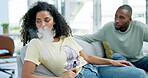 Couple, nicotine and argue about addiction with a woman smoking an e cigarette in the living room of her home. Smoke, habit and lifestyle with an attractive young female smoker in her house to relax