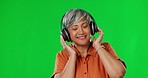 Music, green screen and elderly woman with headphones dance in studio, happy and free on mockup background. Radio, podcast and senior lady dancing, streaming and chilling with online subscription