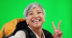 Peace sign, selfie and woman in a studio with green screen with camping or hiking equipment. Happy, smile and portrait of a senior female model taking a picture for trekking by chroma key background.
