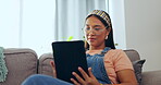 Asian woman, tablet and relax on sofa in living room for social media or streaming entertainment at home. Happy female relaxing on lounge couch browsing, scrolling or searching on technology indoors