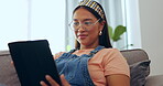 Asian woman, tablet and relax on sofa for social media or streaming entertainment in living room at home. Happy female relaxing on lounge couch browsing, scrolling or searching on technology indoors