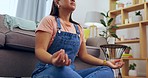 Woman, yoga and meditation on floor in living room for spiritual wellness, health and zen exercise at home. Calm asian female relaxing or meditating by sofa in lounge for stress relief or workout