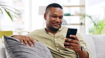 Black man, phone and relax on sofa for social media, communication or networking in living room at home. Happy African American male relaxing on couch with mobile smartphone for browsing or chatting