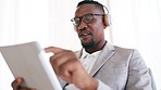 Tablet, headphones and black man in the office listening to music, playlist or album. Dance, technology and professional African business male employee streaming a song or video online in workplace.