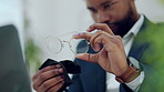 Hands of man cleaning glasses, lens and eye care protection with fabric cloth in office. Closeup of male, business employee and wipe dust on spectacle frames, eyewear and maintenance for clear vision