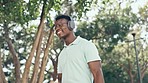 Music, happiness and black man headphones in park, walking with luggage and happy smile. Streaming, wifi and travel, young person listening to audio with freedom and wellness on trip with suitcase.