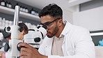 Microscope, analysis and man scientist in a laboratory for research, chemistry and innovation. Healthcare, medical and indian health expert checking chemical, experiment and cancer cure in a lab