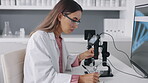 Research, microscope and computer with a woman writing notes while working on innovation in a laboratory. Science, notebook and sample with a young female scientist at work in a lab for breakthrough