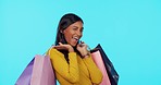 Happy woman, shopping bags and wink in studio for purchase, sale or discount against a blue background. Portrait of female shopper with smile for fashion, buying or gift bag in luxury on mockup